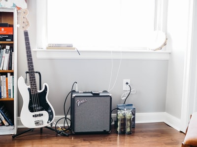 Black white and black strats were configured on the guitar guitar stood beside black fender guitar amplifier
